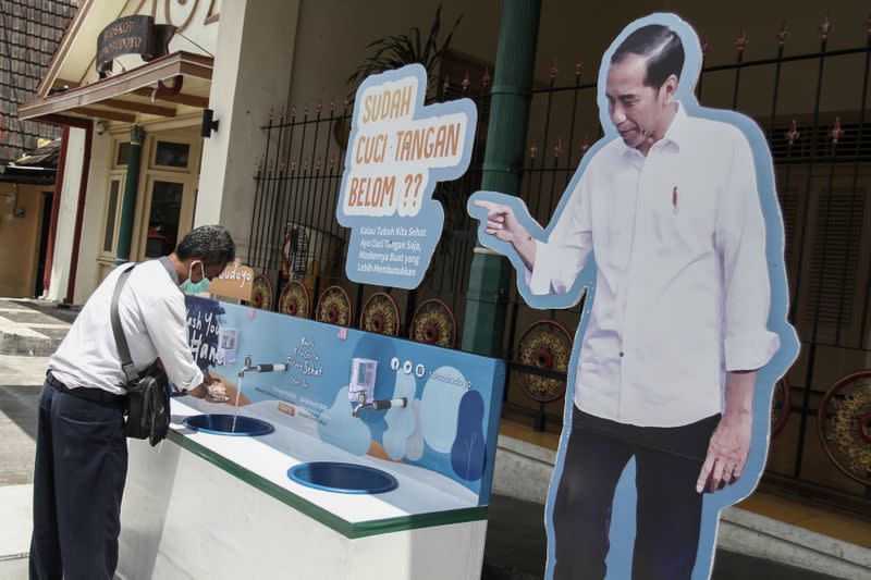 A man washes hands at a hand-washing station to prevent the spread of coronavirus disease (COVID-19)