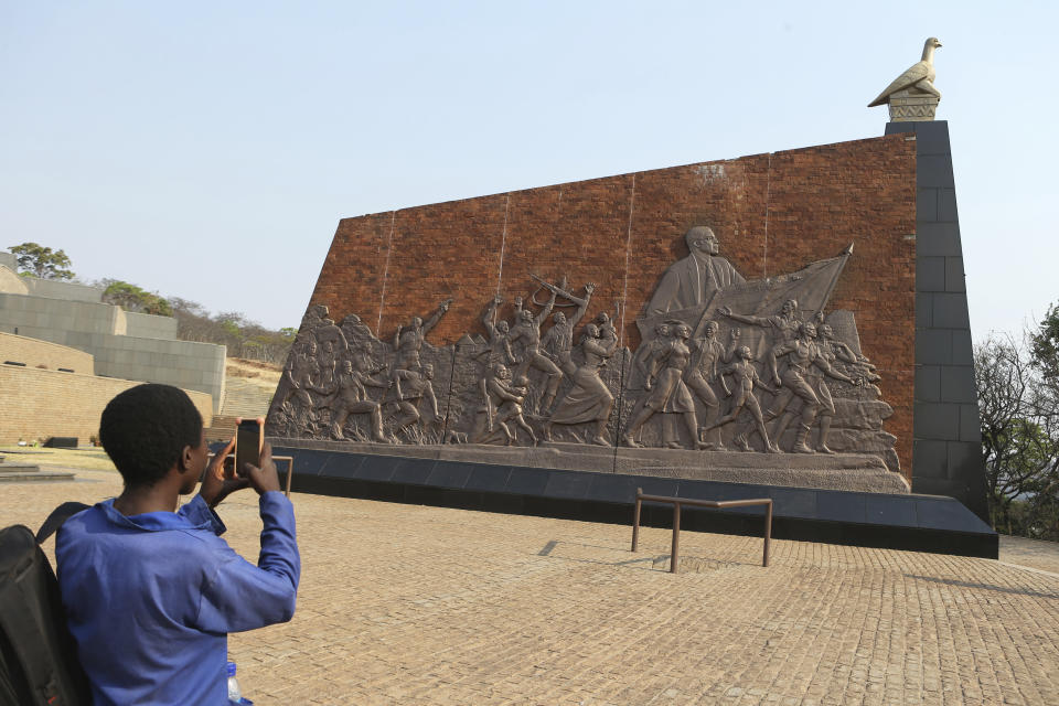 A visitor takes a picture of a work of art showing the late former Zimbabwean leader Robert Mugabe leading the struggle at the National Heroes Acre in Harare,Friday, Sept, 13, 2019. A family spokesman says Mugabe will be buried at the national Heroes' Acre site but it is not yet clear when. (AP Photo/Tsvangirayi Mukwazhi)