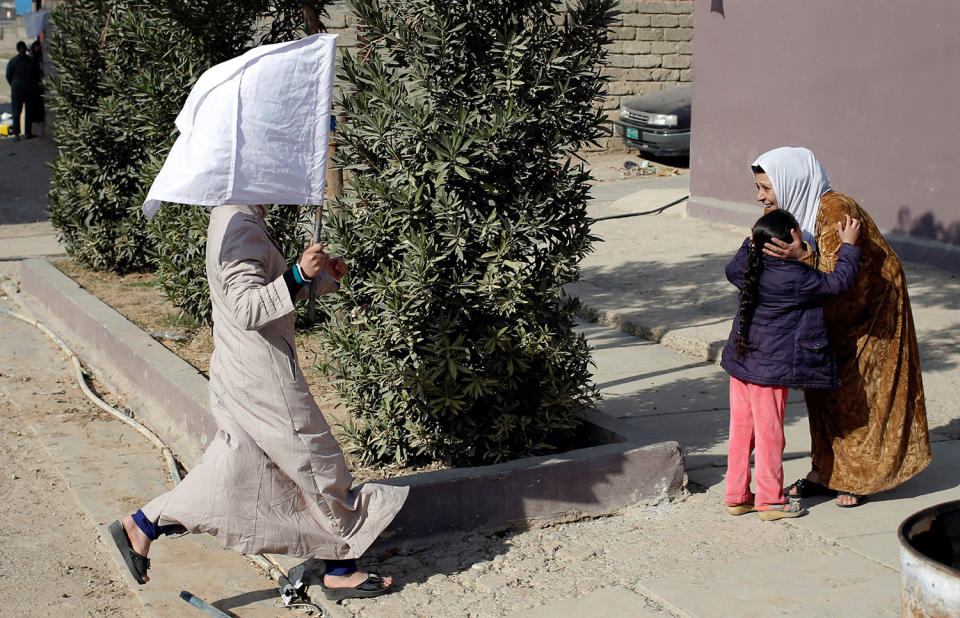 A woman holds up a white flag as she runs to greet her relatives