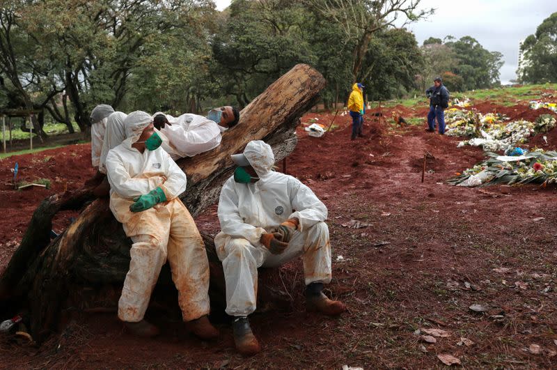 Sepultureros con trajes protectores descansan tras enterrar a a personas en medio del brote de COVID-19 en el cementerio de Vila Formosa, en Sao Paulo, Brasil. 27 de junio de 2020.