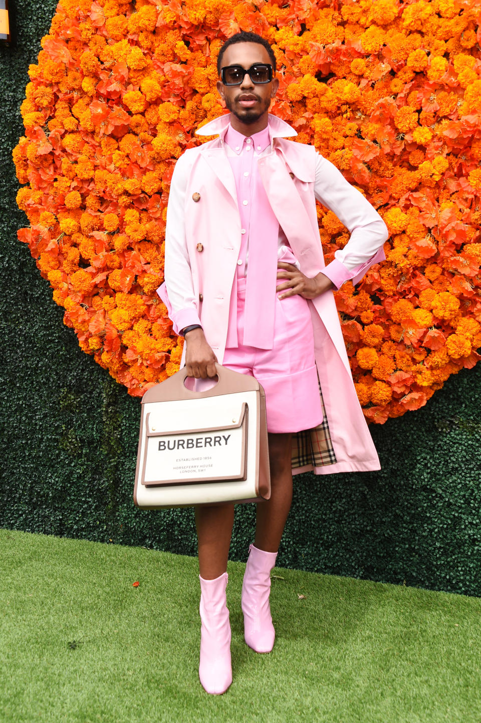 Kalen Allen at an event wearing a dress shirt with matching shorts, trench coat and boots