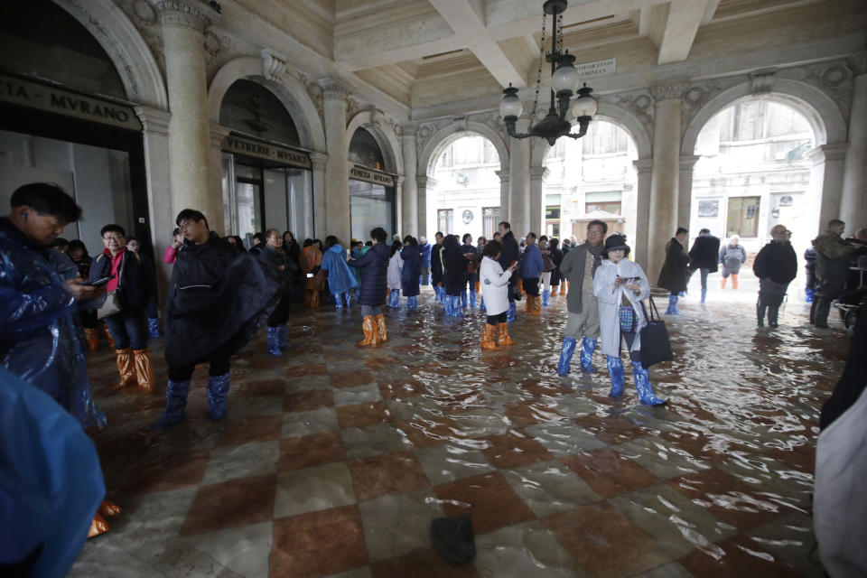 Tourists gather in a flooded St. Mark's Square in Venice, Italy, Friday, Nov. 15, 2019. The high-water mark hit 187 centimeters (74 inches) late Tuesday, Nov. 12, 2019, meaning more than 85% of the city was flooded. The highest level ever recorded was 194 centimeters (76 inches) during infamous flooding in 1966. (AP Photo/Luca Bruno)