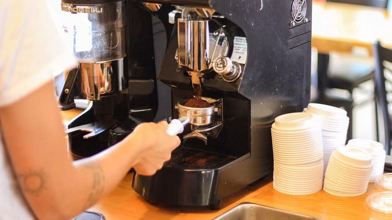 Barista grinding coffee beans on counter