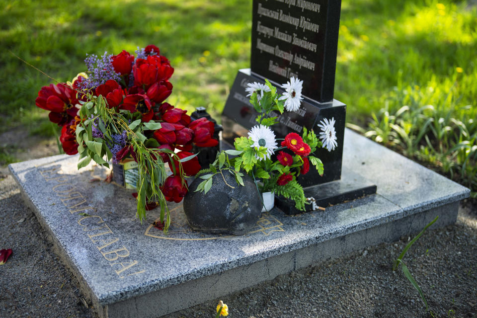 Flowers and a helmet rest at the memorial stone that commemorates the death of six Ukrainian soldiers killed by Russians, in the yard of the Church of the Intercession of the Blessed Virgin Mary in, Lypivka, near Lviv, Ukraine, Sunday, April 28, 2024. This Orthodox Easter season, an extraordinary new church is bringing spiritual comfort to war-weary residents of the Ukrainian village of Lypivka. Two years ago it also provided physical refuge from horrors outside. (AP Photo/Francisco Seco)