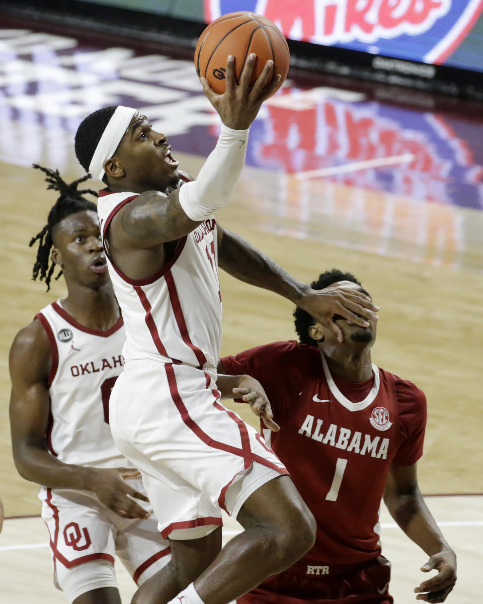 Oklahoma's De'Vion Harmon (11) takes a shot against Alabama's Herbert Jones (1) as Oklahoma's Victor Iwuakor (0) looks on during the second half of an NCAA college basketball game in Norman, Okla., Saturday, Jan. 30, 2021. (AP Photo/Garett Fisbeck)