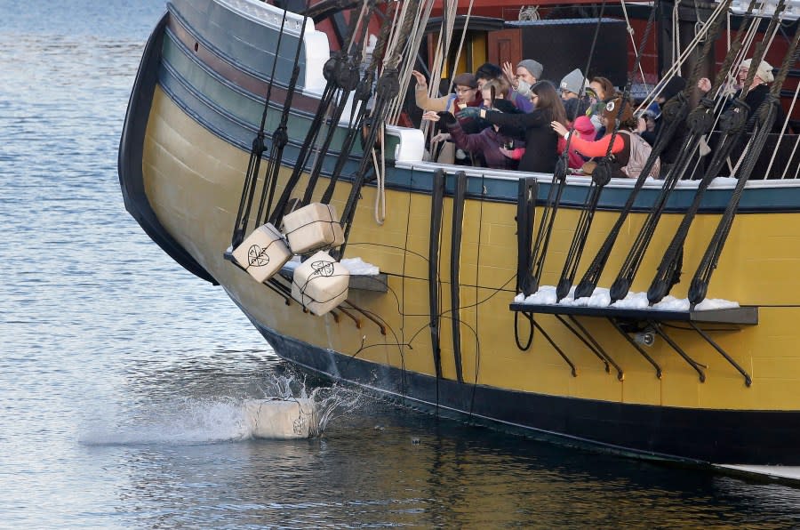 FILE-In this Monday, Dec. 11, 2017 photo, visitors to the Boston Tea Party Museum throw replicas of historic tea containers into Boston Harbor from aboard a replica of the vessel Beaver, in Boston. Patriotic mobs and harbor tea dumping are returning to Boston on Saturday, Dec. 16, 2023, as the city marks the 250th anniversary of the revolutionary protest that preceded America’s independence. (AP Photo/Steven Senne, files)