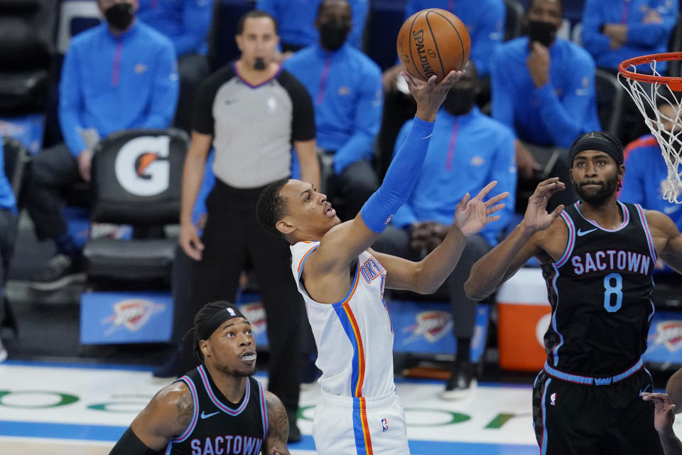 Oklahoma City Thunder forward Darius Bazley, center, shoots between Sacramento Kings center Richaun Holmes, left, and forward Maurice Harkless (8) in the first half of an NBA basketball game Tuesday, May 4, 2021, in Oklahoma City. (AP Photo/Sue Ogrocki)