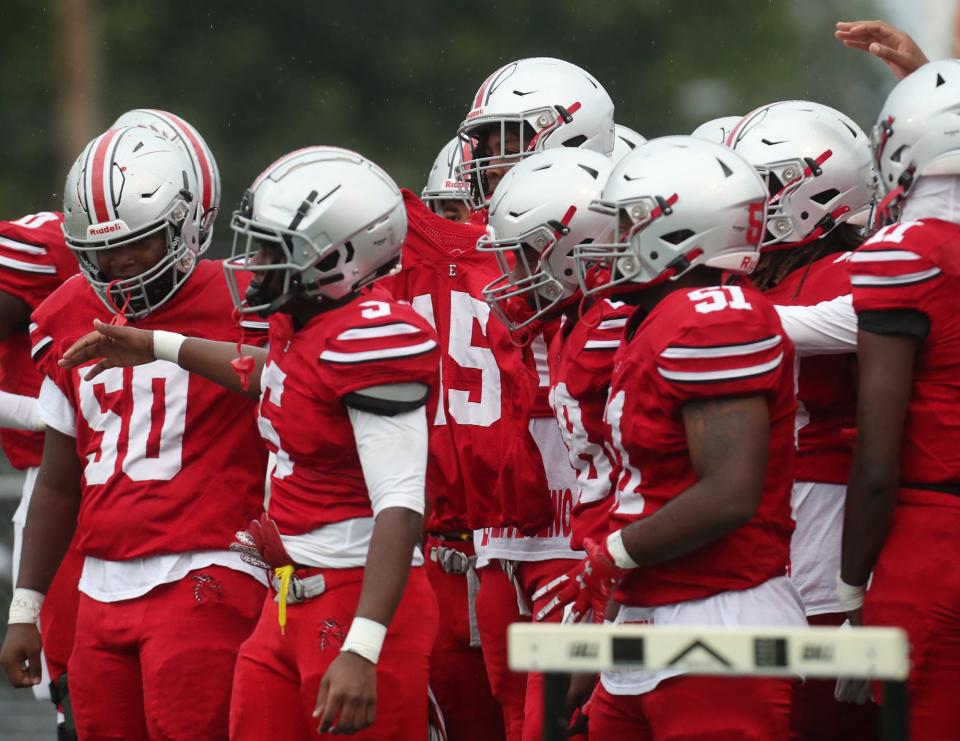 East football players carry the number 15 jersey of their teammate Antenio Louis, who was shot and killed Wednesday, as they get ready to take the field Thursday against Youngstown Chaney at Ellet High School in Akron.