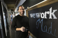 In this Tuesday, Nov. 5, 2019 photo, Lanny Grossman, owner of public relations firm EM50 Communications, poses at a WeWork office space near Grand Central station in New York. Emptier than other WeWorks just blocks away, the space is sometimes dark because too few people show up to trigger enough automatic lighting sensors, Grossman said. The office-sharing company is slashing the lavish spending that fueled the office-sharing company’s breakneck growth while racking up unsustainable losses that ultimately turned off Wall Street investors, forcing it to shelve its initial public offering. (AP Photo/Mark Lennihan)