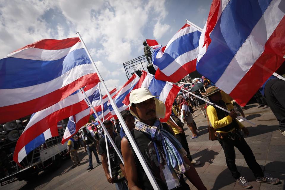 Anti-government protesters carry Thai national flags during a march towards the prime minister's office compound in Bangkok, Thailand, Monday, May 12, 2014. The battle for who holds Thailand's seat of power took on a new twist Monday as leader of anti-government protests Suthep Thaugsuban planned to set up his office at the vacated Government House while the country's new caretaker leader worked from a makeshift, suburban outpost. (AP Photo/Vincent Thian)