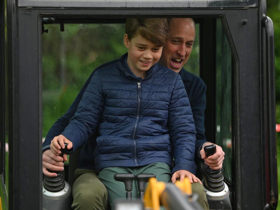 Prince William and Prince George drive an excavator during a volunteer day as part of King Charles' coronation events in May 2023.