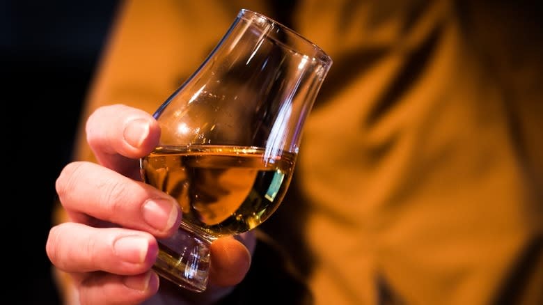 Hand holding whiskey in Glencairn glass