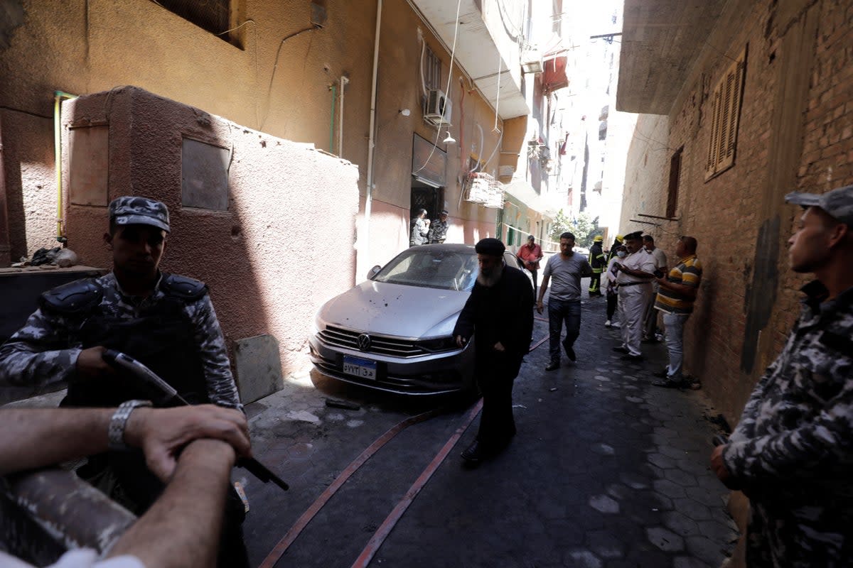 People and policemen stand near the scene where a deadly fire broke out at the Abu Sifin church in Giza, Egypt (REUTERS)