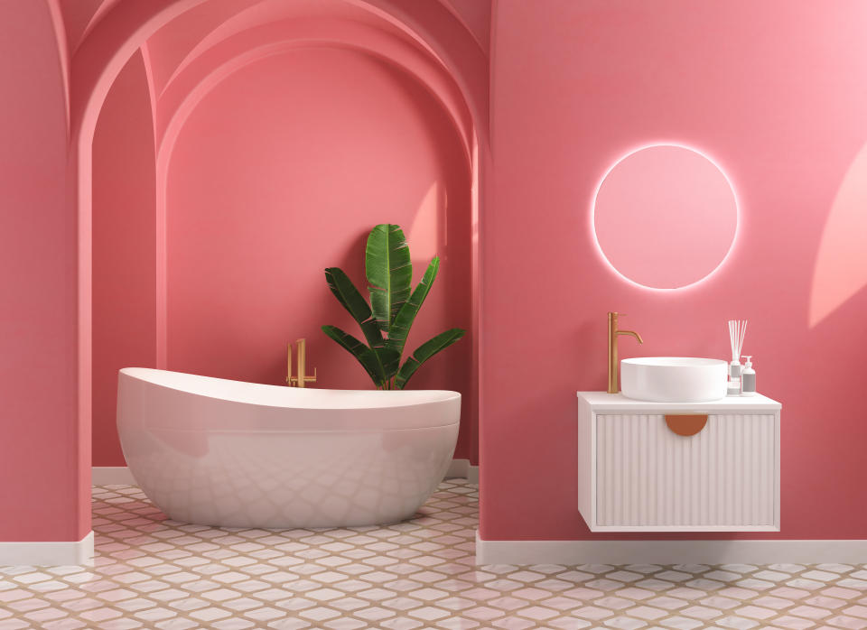 Modern mid century and minimalist bathroom interior, coral decor concept, modern white bathroom cabinet and white bathtub with coral wall on concrete floor. 3d rendering