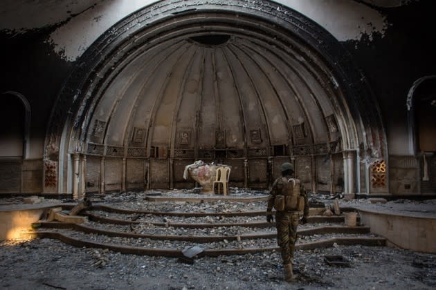 A soldier from a Christian military organization walks through a church destroyed by ISIS in Qaraqosh, Iraq, on November 8, 2016. Now that Iraqi forces have retaken Qaraqosh—formerly the country’s largest Christian city—some residents are slowly returning. <a href="https://www.theatlantic.com/photo/2017/04/iraqi-christians-slowly-return-to-war-damaged-qaraqosh/524601/" rel="nofollow noopener" target="_blank" data-ylk="slk:More photos here;elm:context_link;itc:0;sec:content-canvas" class="link ">More photos here</a>. (Chris McGrath / Getty)