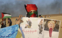 A Palestinian woman holds photos of the U.S. President Donald Trump during a protest on the beach at the border with Israel near Beit Lahiya, northern Gaza Strip, Monday, Sept. 17, 2018. (AP Photo/Adel Hana)