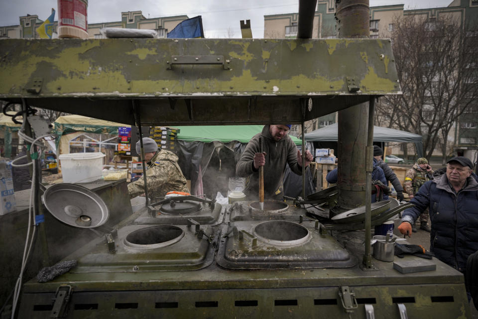 People cook outdoors for Ukrainian servicemen and civil defense members serving in Kyiv, Ukraine, Monday, March 7, 2022. The United Nations is unable to meet the needs of millions of civilians caught in conflict in Ukraine today and is urging safe passage for people to go "in the direction they choose" and for humanitarian supplies to get to areas of hostilities, according to the U.N. humanitarian chief. (AP Photo/Vadim Ghirda)