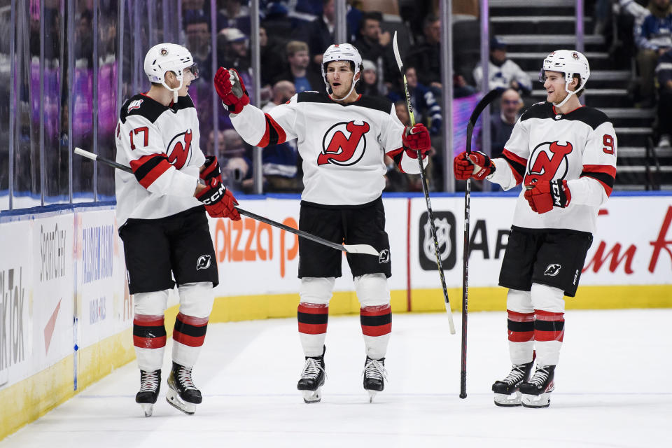 New Jersey Devils center Yegor Sharangovich (17), defenseman John Marino (6) and center Dawson Mercer (91) celebrate after Sharangovich scored against the Toronto Maple Leafs during overtime in an NHL hockey game Thursday, Nov. 17, 2022, in Toronto. (Christopher Katsarov/The Canadian Press via AP)