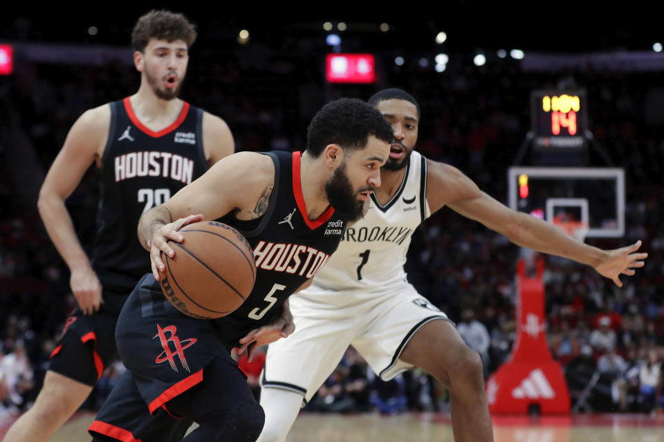 Houston Rockets guard Fred VanVleet (5) drives around Brooklyn Nets forward Mikal Bridges (1) and center Alperen Sengun, left, looks on during the first half of an NBA basketball game Wednesday, Jan. 3, 2024, in Houston. (AP Photo/Michael Wyke)