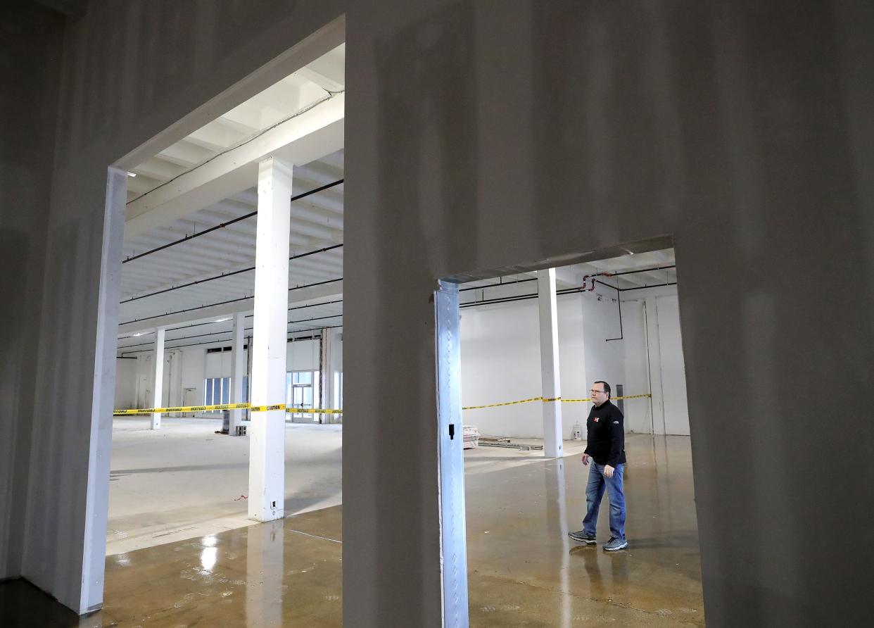 OnQ Solutions' Senior Director of Production Greg Brumbaugh is framed by a doorway that separates the front entrance from the production area in the business' new space inside the former Chapel Hill Mall.