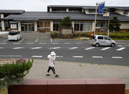 A woman walks on a street as a car (R) used for a sharing service supported by Uber drives past in Kyotango, Kyoto prefecture, Japan May 26, 2016. REUTERS/Junko Fujita