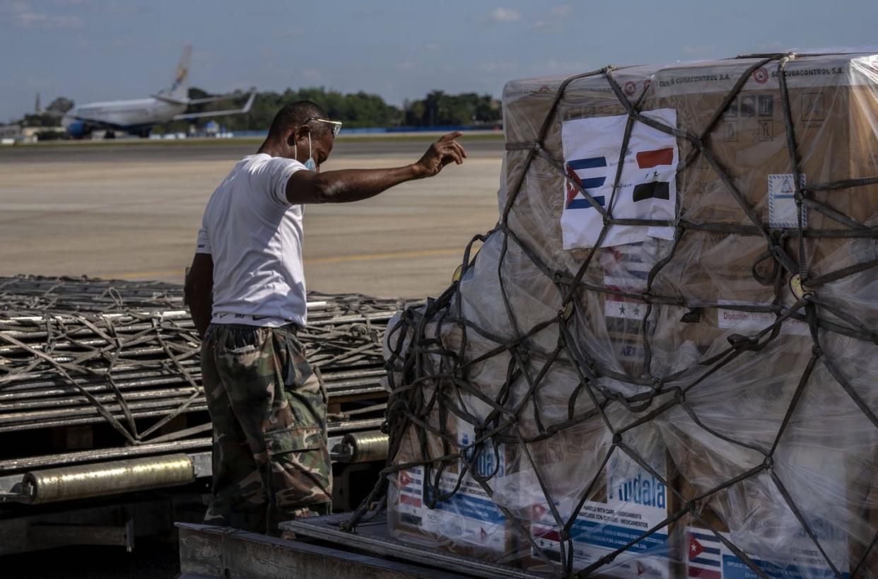 <span class="caption">A ground crew member directs the loading of a shipment of Cuba's homegrown COVID-19 vaccines donated to Syria, on the tarmac of the Jose Marti International Airport, in Havana, on Jan. 7, 2022.</span> <span class="attribution"><span class="source"> (AP Photo / Ramon Espinosa)</span></span>
