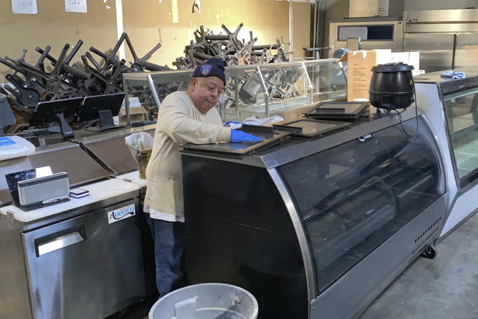 An employee cleans used equipment for sale inside the warehouse of American Restaurant Supply, which is packed with appliances and furniture from restaurants that have shut down during the pandemic, in San Leandro, Calif., on Jan. 14, 2021. The pandemic has forced thousands of restaurants to permanently shut their doors as dining restrictions keep customers away. But the unprecedented closures have created a business boom for commercial auctioneers that buy and sell used restaurant equipment. (AP Photo/Terry Chea)