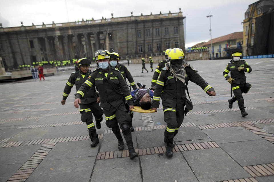 Police carry an anti-government protesters affected by tear gas after clashes at the Bolivar square in downtown Bogota, Colombia, Friday, Nov. 22, 2019. Labor unions and student leaders called on Colombians to bang pots and pans Friday evening in another act of protest while authorities announced three people had died in overnight clashes with police after demonstrations during a nationwide strike. (AP Photo/Ivan Valencia)