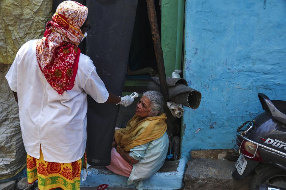 An Indian health worker checks body temperature of a woman during a door-to-door survey being conducted as a precaution against COVID-19 in Hyderabad, India, Thursday, May 6, 2021. (AP Photo/Mahesh Kumar A.)