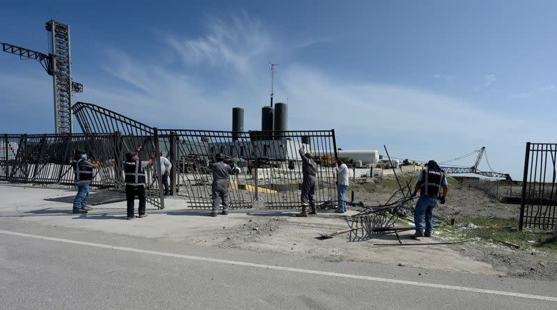 FILE PHOTO: Workers clean up debris on SpaceX's launchpad after their next-generation Starship and super heavy rocket launched, causing damage at the company's Boca Chica facility, near Brownsville
