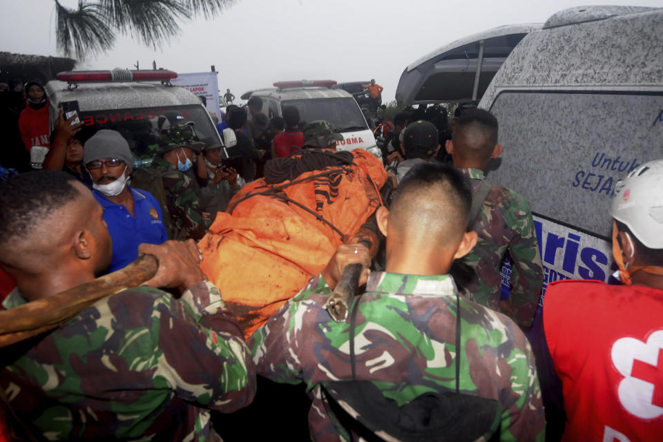 Rescuers carry the body of a victim of the eruption of Mount Marapi into an ambulance in Batu Palano, West Sumatra, Indonesia, Tuesday, Dec. 5, 2023. Rescuers searching the hazardous slopes of the volcano found more bodies of climbers who were caught by a surprise weekend eruption, raising the number of confirmed dead to nearly two dozens, officials said Tuesday. (AP Photo/Ardhy Fernando)