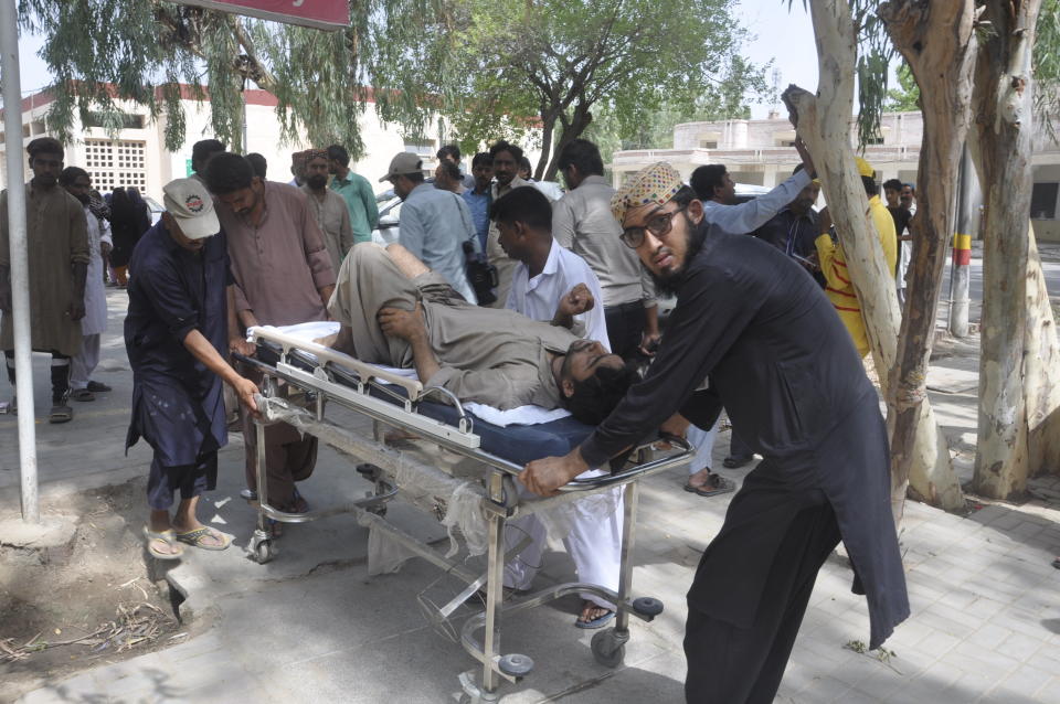 People rush an injured passenger to a hospital in Rahim Yar Khan, Pakistan, Thursday, July 11, 2019. A passenger train rammed into a freight train in southern Pakistan on Thursday, killing many people and injuring others, an official said. (AP Photo/Waleed Saddique)