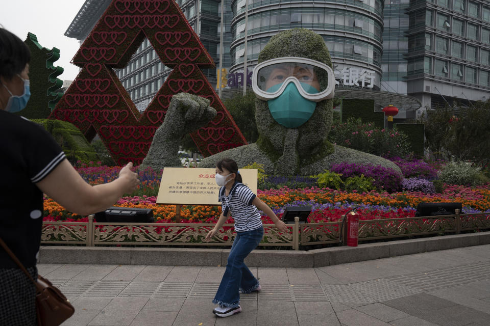 A Chinese girl wearing a mask to protect from the coronavirus runs past a floral decoration, honoring China's frontline workers who fought the COVID-19 outbreak, setup for the National Day holidays in Beijing on Monday, Sept. 28, 2020. Negative perceptions of China have increased sharply in many of the world's advanced economies, especially in Australia and the U.K., a new survey from the Pew Research Center showed Tuesday, Oct. 6, 2020. (AP Photo/Ng Han Guan)