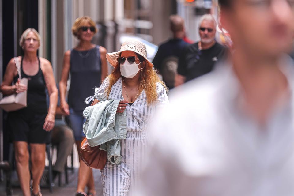 A woman in a mask walks through downtown Austin. Masks should still be worn if you have recently been sick or have illnesses that put you at risk for severe infection.