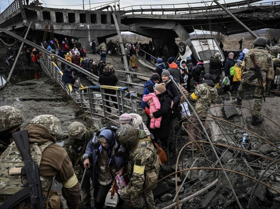 People cross a destroyed bridge as they evacuate the city of Irpin, northwest of Kyiv, during heavy shelling (AFP via Getty Images)