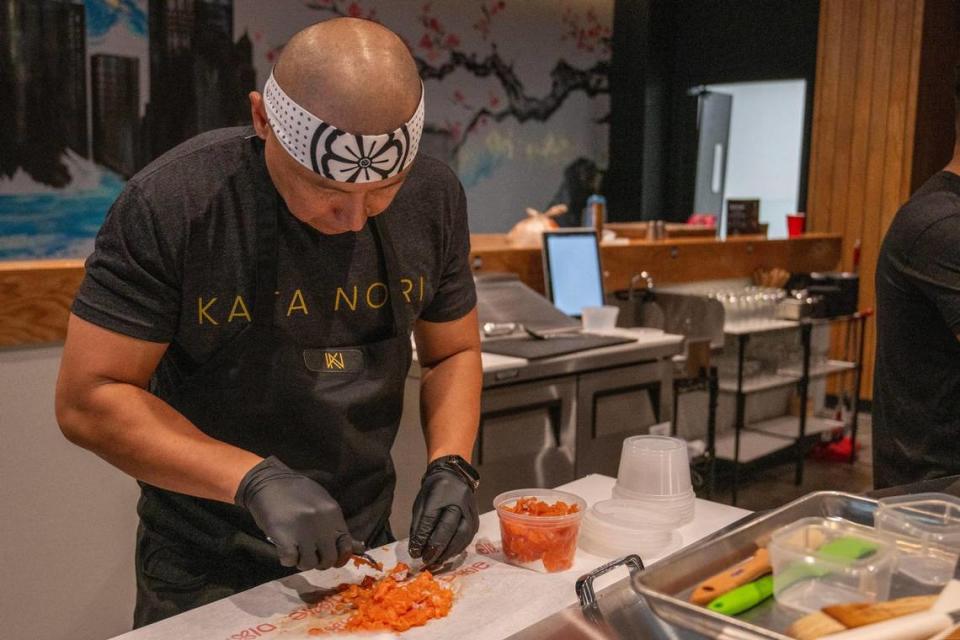 Avalon Cortez scrapes salmon with a spoon behind the counter at Kata Nori.