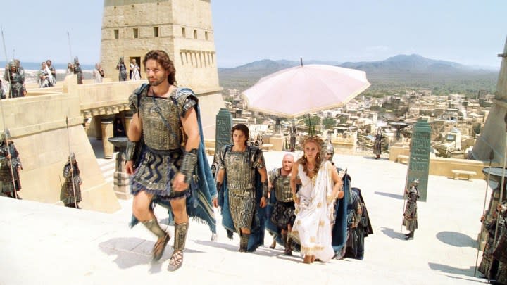 Eric Bana as Hector climbing a set of stairs followed by Paris and Helen in the film Troy.