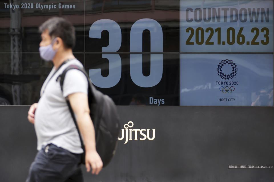 A man wearing a mask against the spread of the new coronavirus walks in front of a countdown calendar showing 30 days to start Tokyo 2020 Olympics Wednesday, June 23, 2021, in Tokyo. (AP Photo/Eugene Hoshiko)