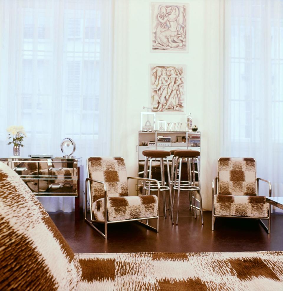 The library-workroom in Lagerfeld's former apartment in Paris features steel-framed armchairs and a daybed from the 1930s. Two drawings by René Buthaud sit above a mirrored bar.