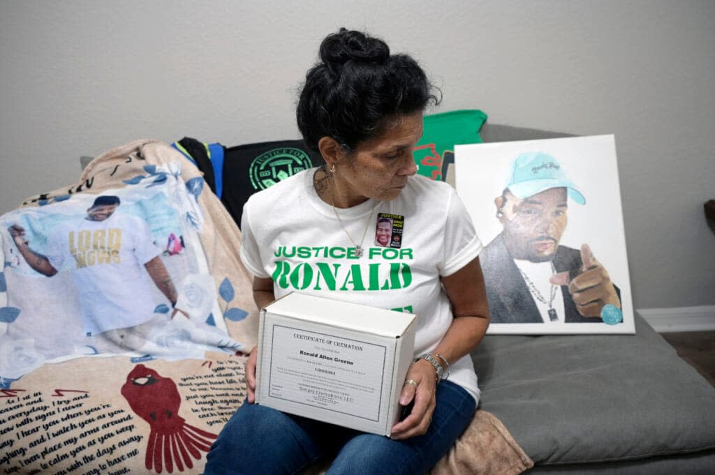 Mona Hardin holds the boxed ashes of her son, Ronald Greene, while sitting items bearing his likeness Saturday, Dec. 4, 2021, in Orlando, Fla. After a more than two-year federal probe, still none of the officers involved has been charged. (AP Photo/Phelan M. Ebenhack)