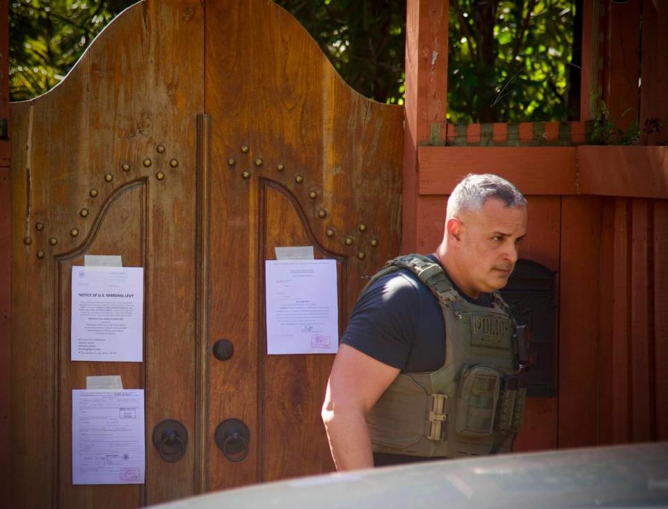 A U.S. Marshal walks away from the front door to Joe Carollo’s residence in Coconut Grove after posting notices on Friday, Feb. 2, 2024. U.S. Marshals began the process to seize the property after he lost a civil trial accusing him of misusing his public office.