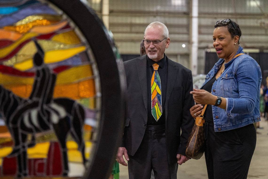 Artist Steven Bolt wears a stained glass tie as he discusses his heart display titled “Illuminated Heartland Vista” with visitor Donease Smith Friday during the Parade of Hearts reveal kickoff event.