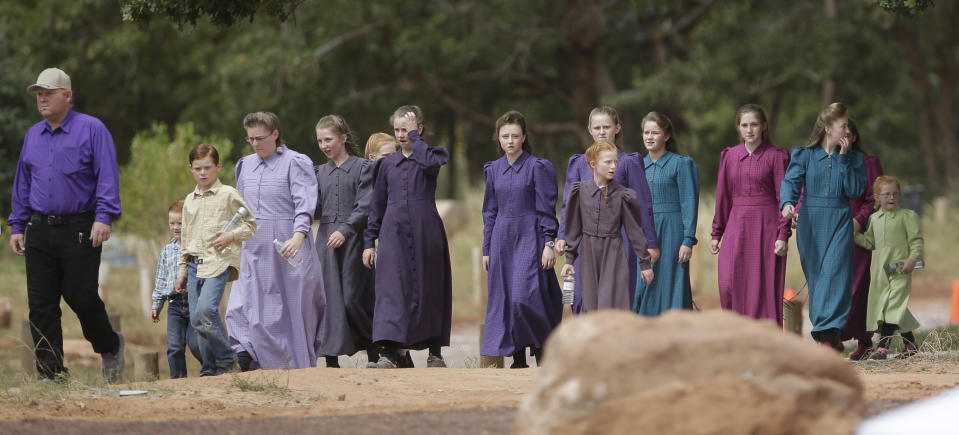 FILE - In this Sept. 26, 2015, file photo, people attend a memorial service in Hildale, Utah, for 12 women and children swept away in a deadly flash flood in a community on the Utah-Arizona border. The community has been home for more than a century to a polygamous sect that is an offshoot of mainstream Mormonism. The slaying in Mexico of nine people who belonged to a Mormon offshoot community where some people practice polygamy shines a new spotlight on the ongoing struggle for the mainstream church to fight the association with plural marriage groups because of its past. (AP Photo/Rick Bowmer)