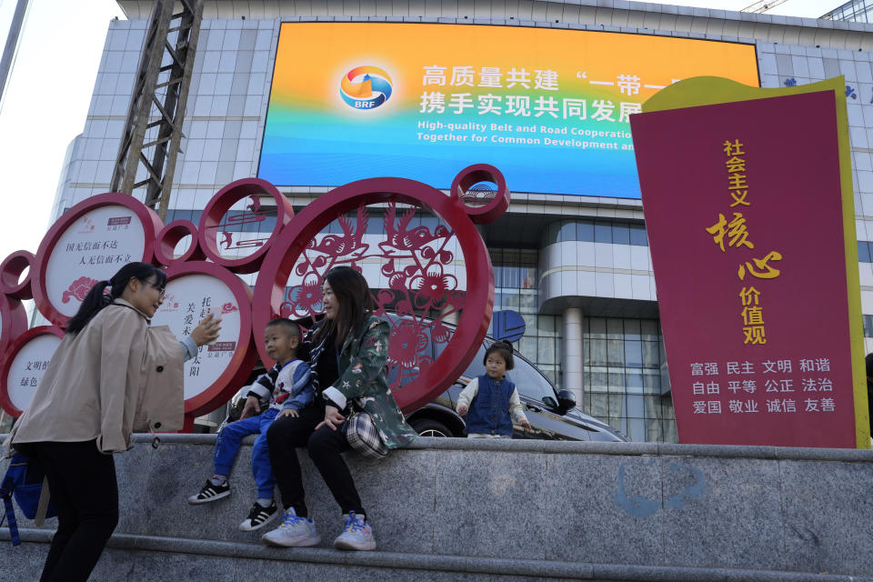 FILE - Residents rest near a display for the upcoming Third Belt and Road Forum and propaganda Chinese socialist values in Beijing, Monday, Oct. 16, 2023. China's Belt and Road Initiative looks to become smaller and greener after a decade of big projects that boosted trade but left big debts and raised environmental concerns. (AP Photo/Ng Han Guan)