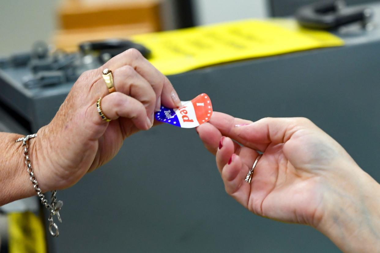 A poll worker gives an "I voted" sticker to a voter during the school board election on Tuesday, May 18, 2021 in Sioux Falls.