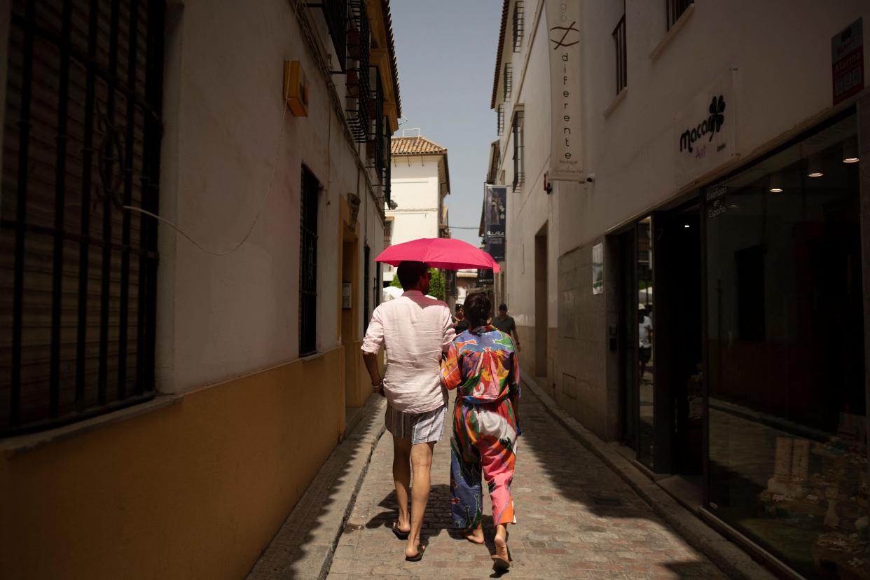 Tourists protect themselves from the sun using an umbrella during a heatwave in Cordoba in Cordoba, 8 August (AFP via Getty Images)