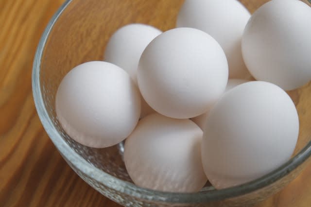 A small bowl filled with eggs on a hardwood counter.