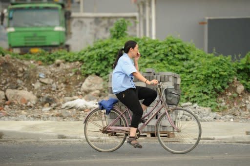 A woman on a bicycle covers her nose against the stench rising from a garbage dump in Songjiang district. Residents claim the incinerator could affect the health of hundreds of thousands of people and call for moving the landfill, which towers up to 17 metres and covers an area the size of a football field