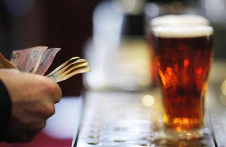 A customer pays for a Fosters beer at the Occidental Hotel in central Sydney June 21, 2011. REUTERS/Tim Wimborne