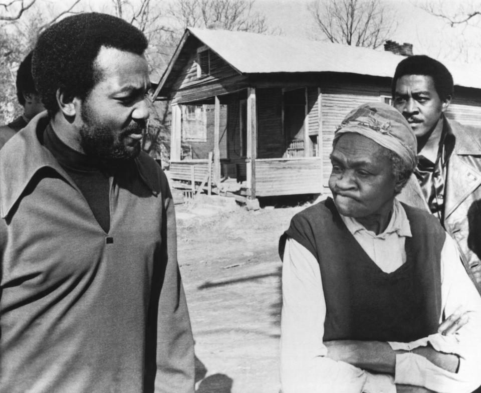 FILE - Former football great Jim Brown, left, President of the Black Economic Union, confers with Mrs. Anne Faulkner, 74, in her poor neighborhood at Holly Springs, Miss., Feb. 11, 1970. Brown led about 25 black athletes for the firsthand look at conditions his BEU hopes to improve. In background is Leroy Kelly of the Cleveland Browns. (AP Photo/File)
